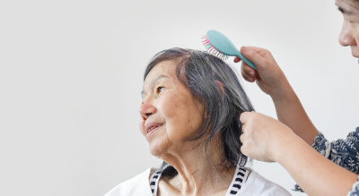 caregiver combing senior woman hair