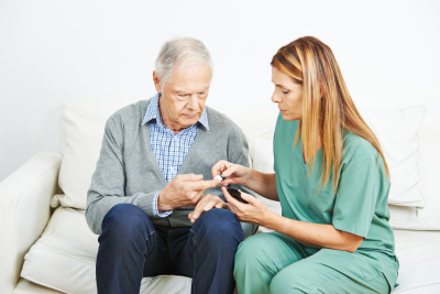 caregiver checking senior's blood sugar