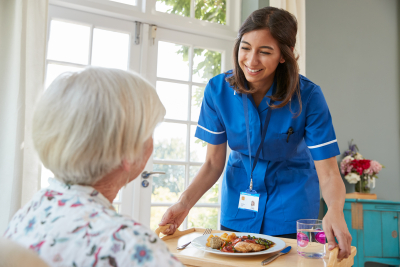 woman giving food to senior